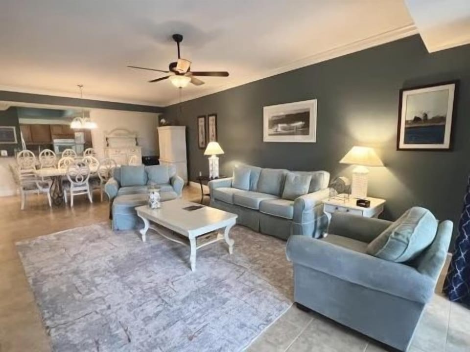 Living area with a plush sofa, warm lighting, and easy access to the kitchen and balcony