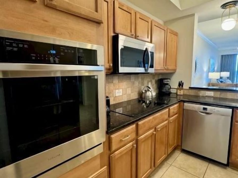 Kitchen with stone counters, kitchen bar seating for three, and full-sized stainless appliances