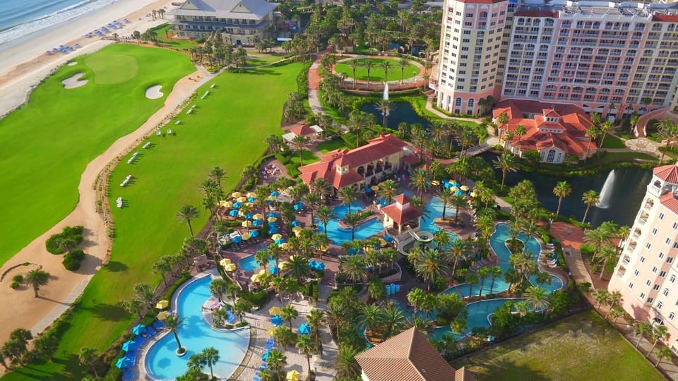 Aerial view of the pool complex with colourful umbrellas and palm trees