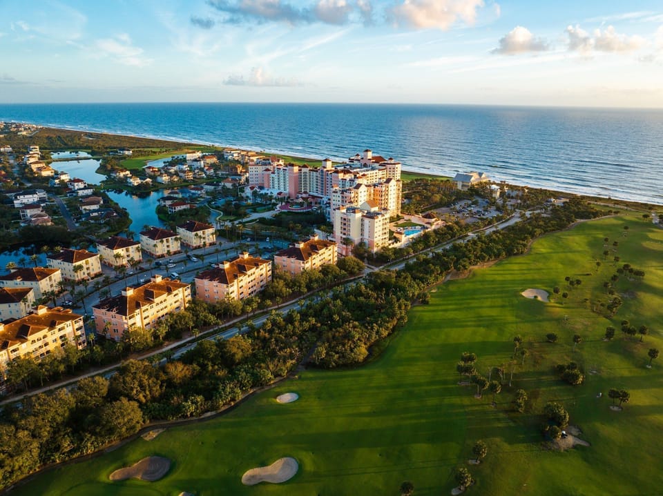 Aerial view of the resort complex with hotel tower, golf courses, and ocean beyond