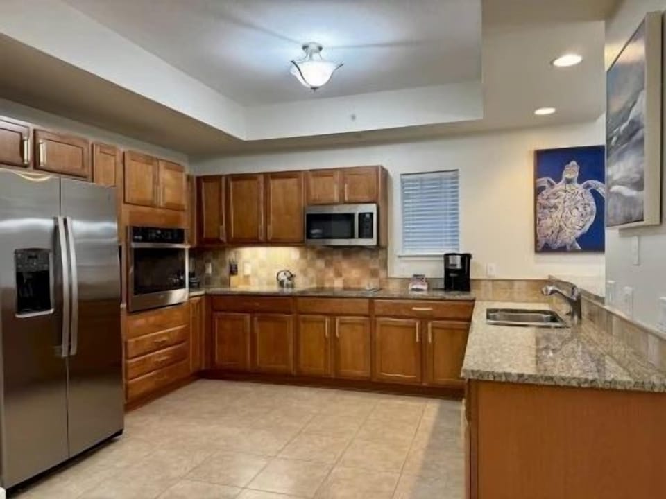 Kitchen with rich wood cabinetry, polished granite counters, and full-sized stainless appliances