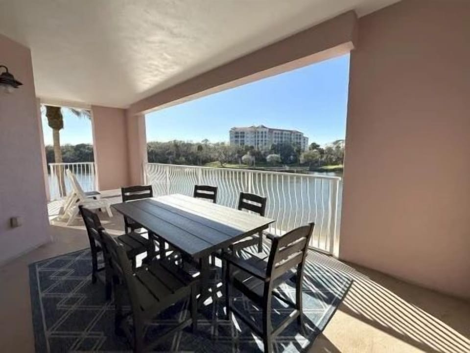 Balcony dining area with a black rectangular table and six black chairs, waterway beyond