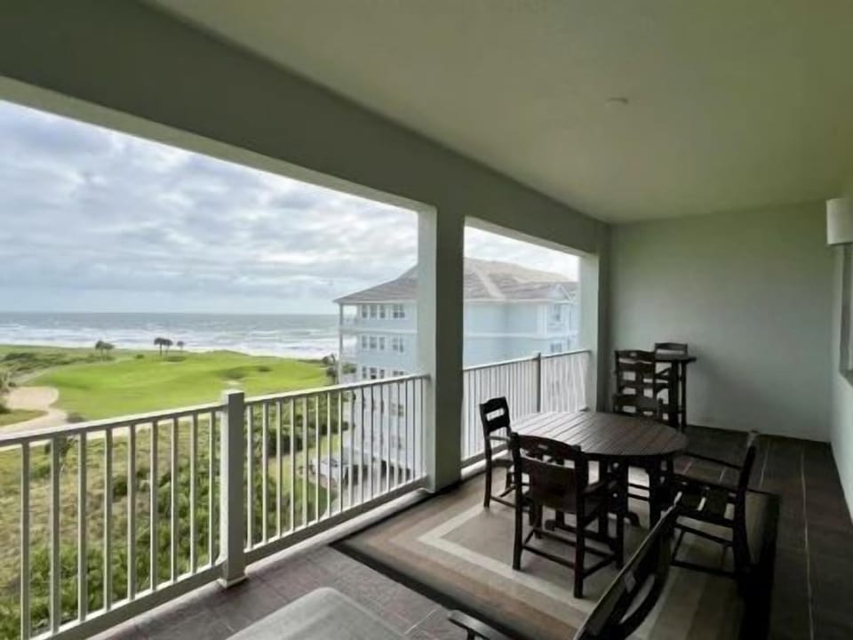 Private balcony with seating overlooking ocean waves and lush golf course greens below
