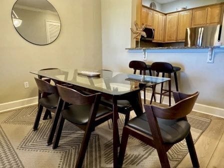 Glass dining table with six seats beneath a warm pendant light