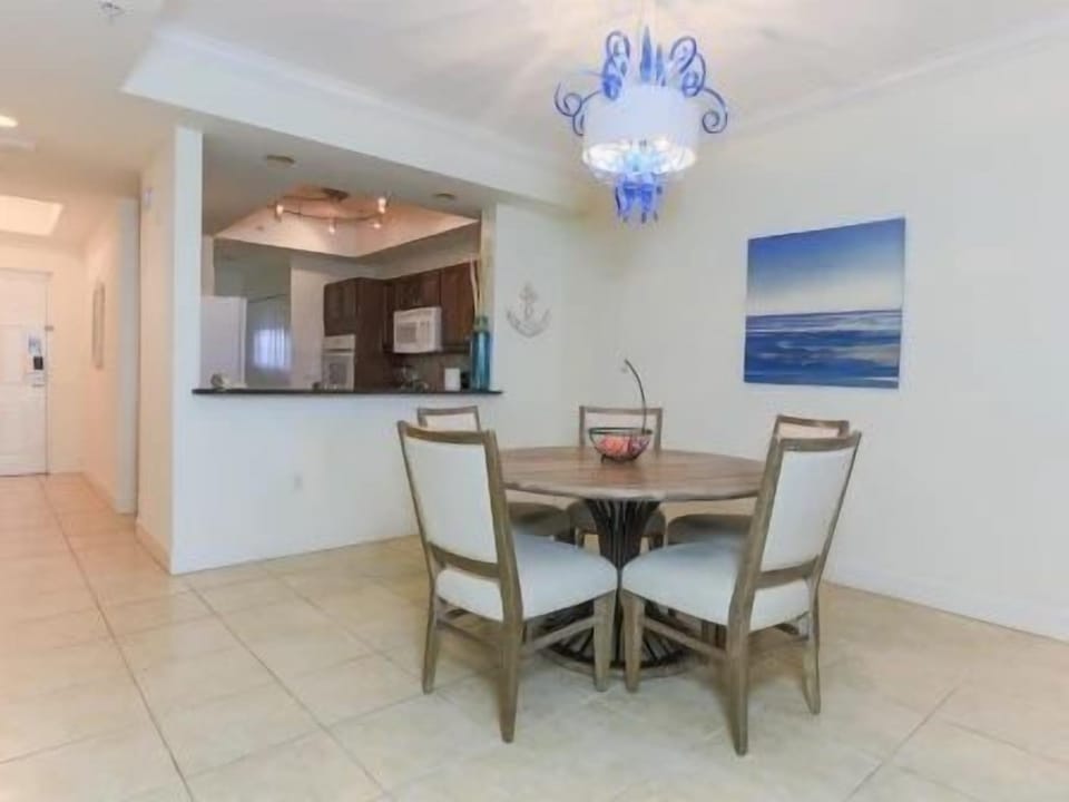 Dining area with a round wooden table, four upholstered chairs, and a chandelier above