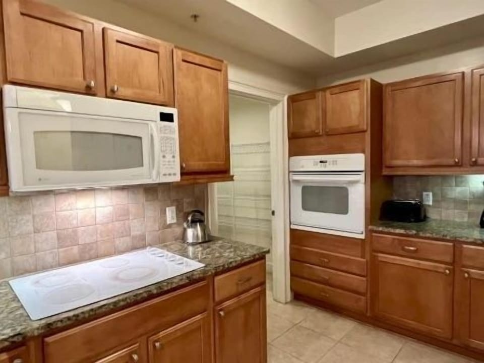 Kitchen with warm wood cabinetry, granite counters, and a two-seat kitchen bar