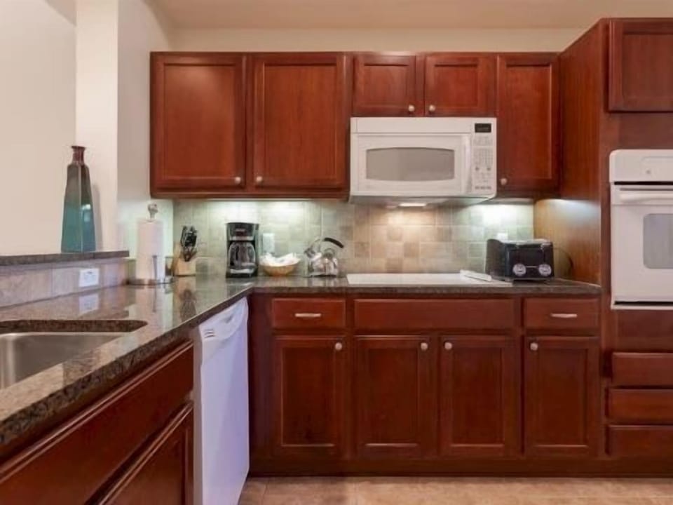 Kitchen with rich wood cabinetry, granite counters, and full-sized appliances for group cooking