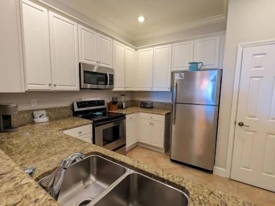 Bright kitchen with stainless appliances, granite counters, and a three-seat kitchen bar