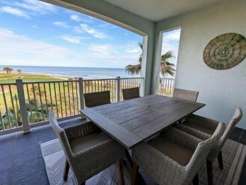 Private balcony with wraparound ocean and golf course views — room for al fresco dining under the palms