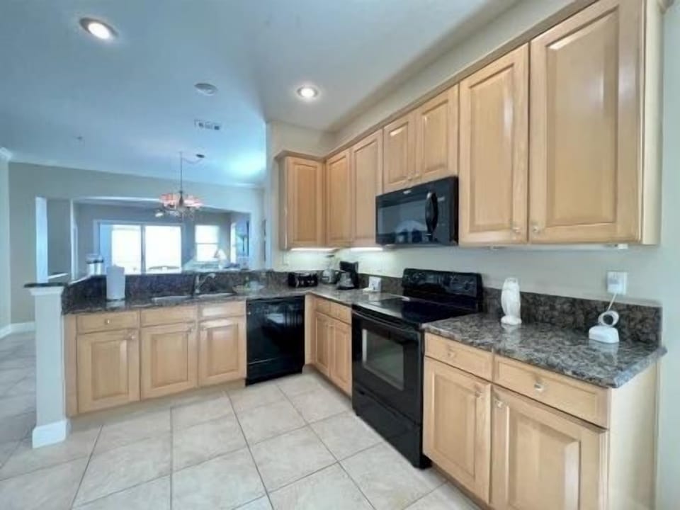Kitchen with warm wood cabinetry, black appliances, and full counter space for group cooking