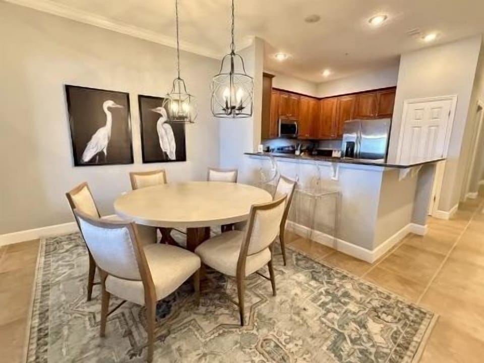 Round dining table with six seats beneath a statement pendant light fixture