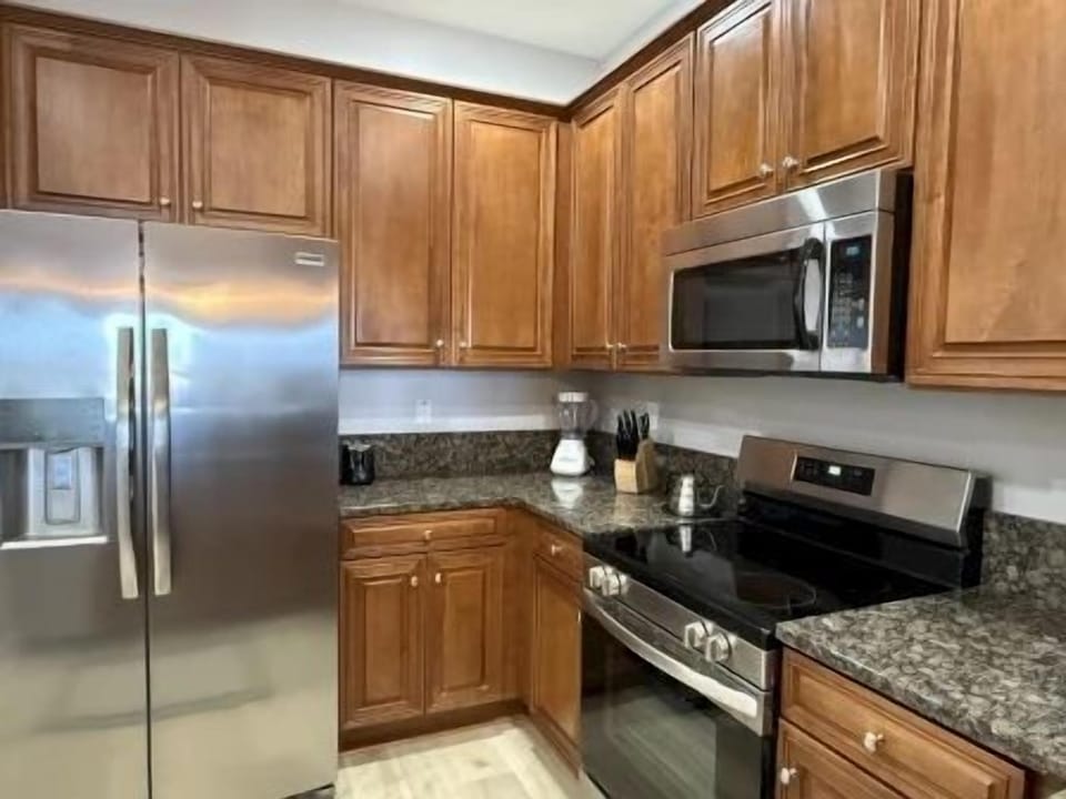 Kitchen with rich wood cabinetry, granite counters, and full-sized appliances for group cooking