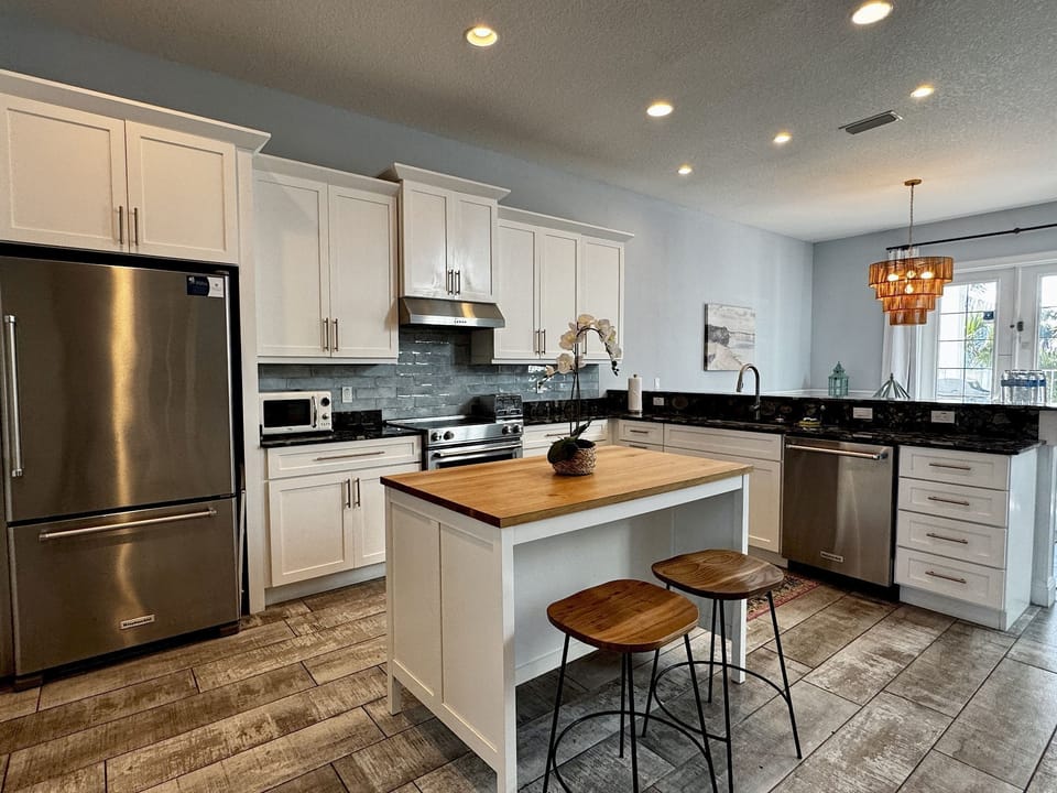 Fully equipped kitchen with stainless steel appliances, kitchen bar, and blue tile accents