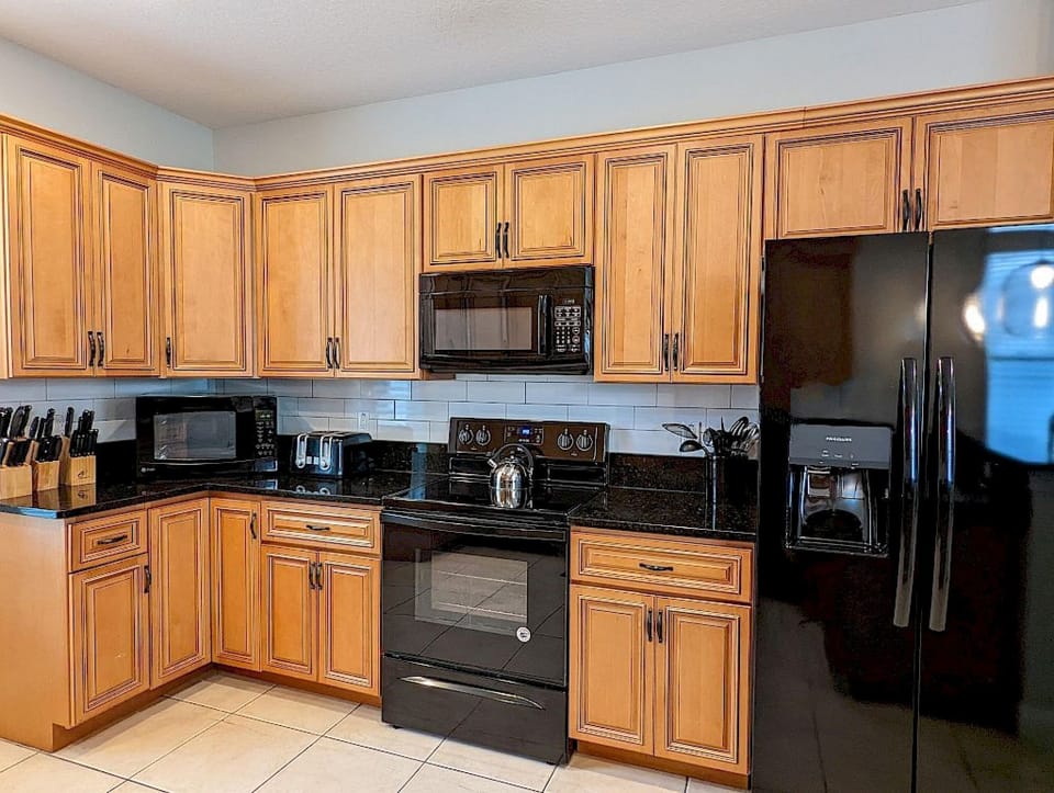 Fully equipped kitchen with dark granite counters, rich wood cabinetry, and full-sized stainless appliances