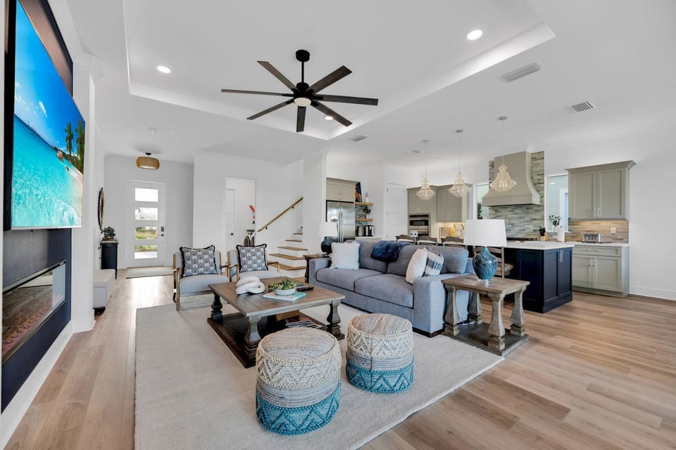 Open living and dining area with large flat-screen TV, modern seating, and natural light throughout