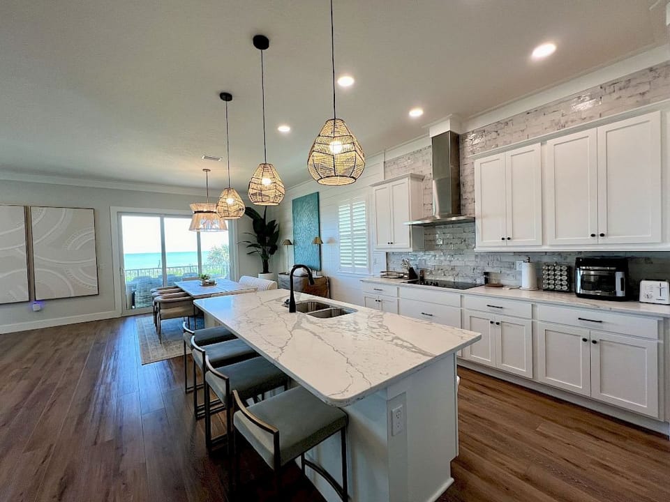 Kitchen with marble-look island, kitchen bar seating, woven pendant lights, and full-sized appliances