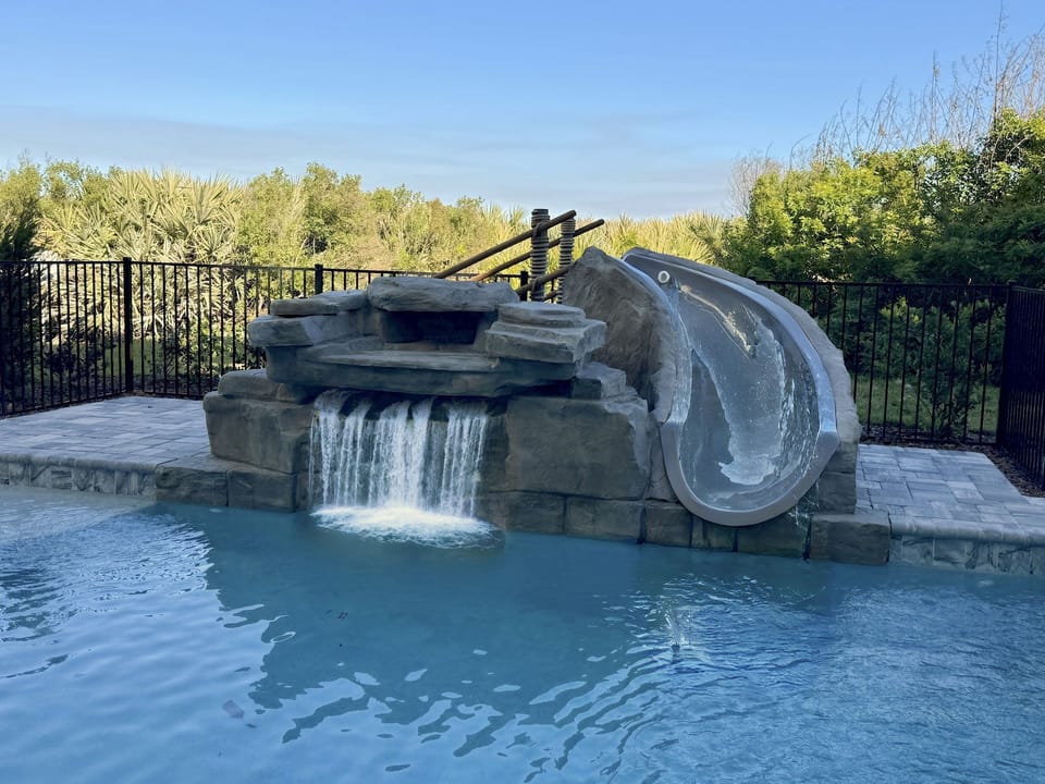 Private pool with waterfall feature and clear blue water — multiple balconies overlook from above