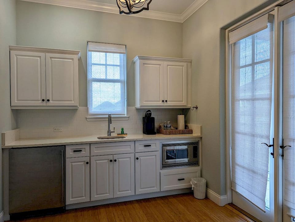 Kitchenette with white cabinetry, microwave, stainless refrigerator, and glass doors to the outside