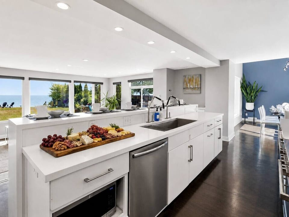 The bright main kitchen opens to the living and dining areas, keeping Lake Michigan in view while the group cooks and gathers.