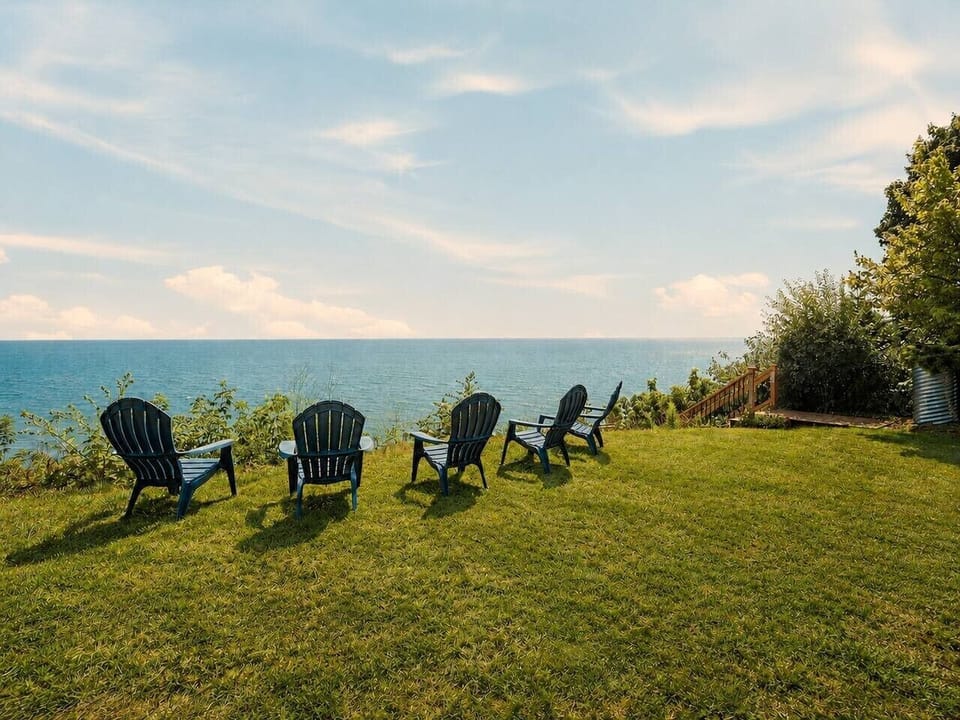 Adirondack chairs face Lake Michigan from the bluff-top lawn—one of the best places at the home for sunrise coffee.