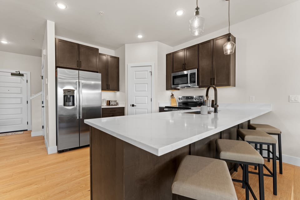 Your fully equipped kitchen invites you to gather around the spacious island, where rich wood cabinetry and sleek countertops set the stage for memorable meals and easy mornings together.