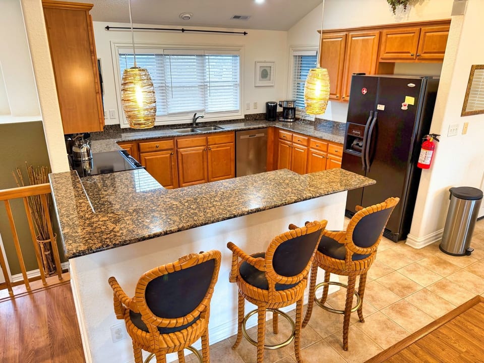 Sunny kitchen with granite bar, pendant lights, and coffee station.