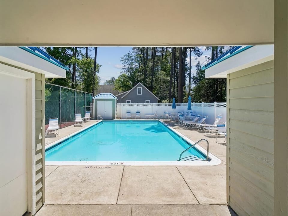 Community pool with lounge chairs and shade umbrellas -- cool off between beach days