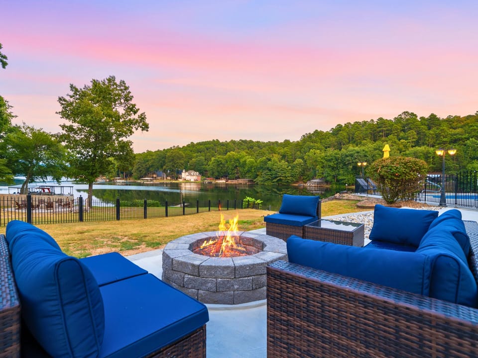 Enjoy peaceful evenings by the pool with the outdoor fire pit as a cozy gathering spot, surrounded by comfortable seating and a beautiful lakeside atmosphere.