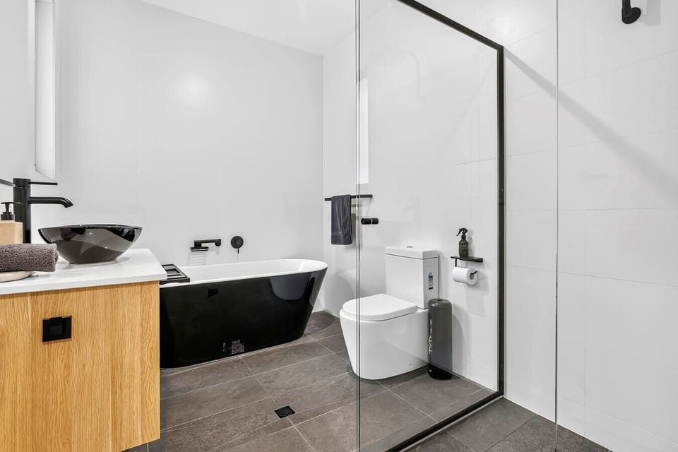 Crisp white bathroom with walk-in shower, black tapware and timber vanity
