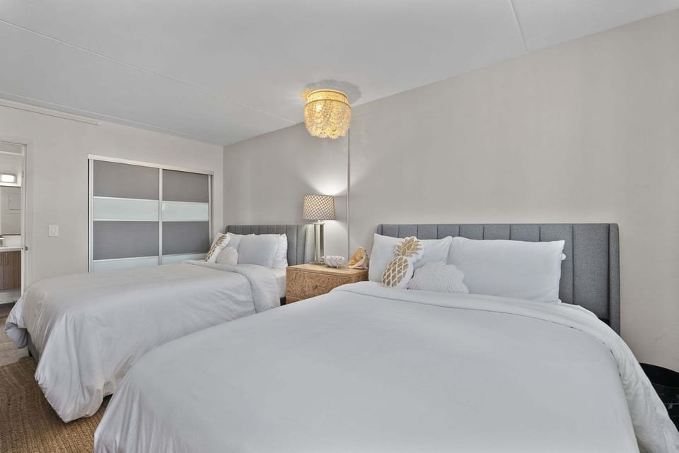 The bedroom features a pair of queen beds, a TV, & an ensuite bath​