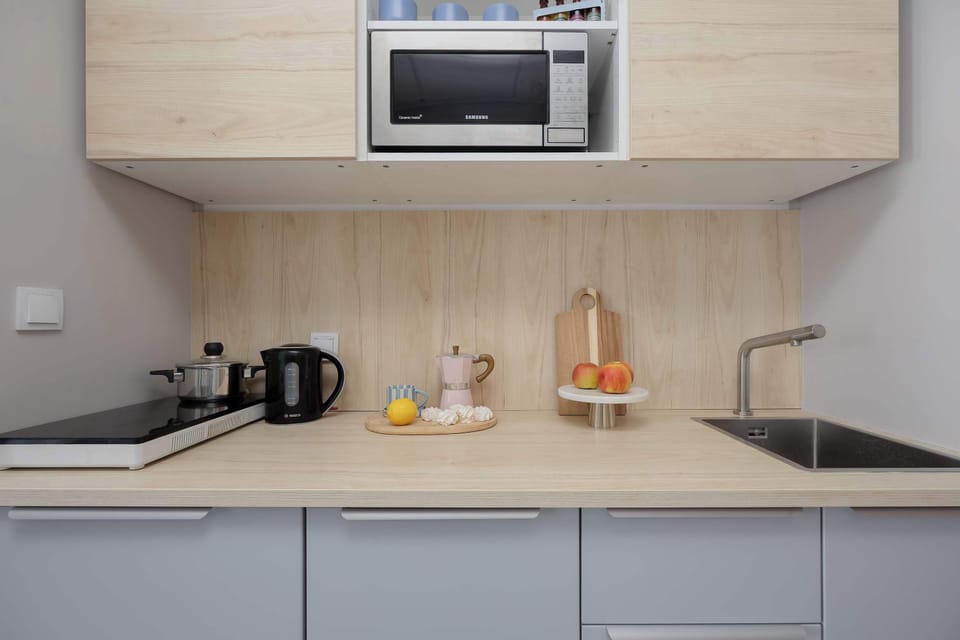 Modern kitchenette equipped with a microwave, induction hob, kettle, and essential appliances for everyday cooking.