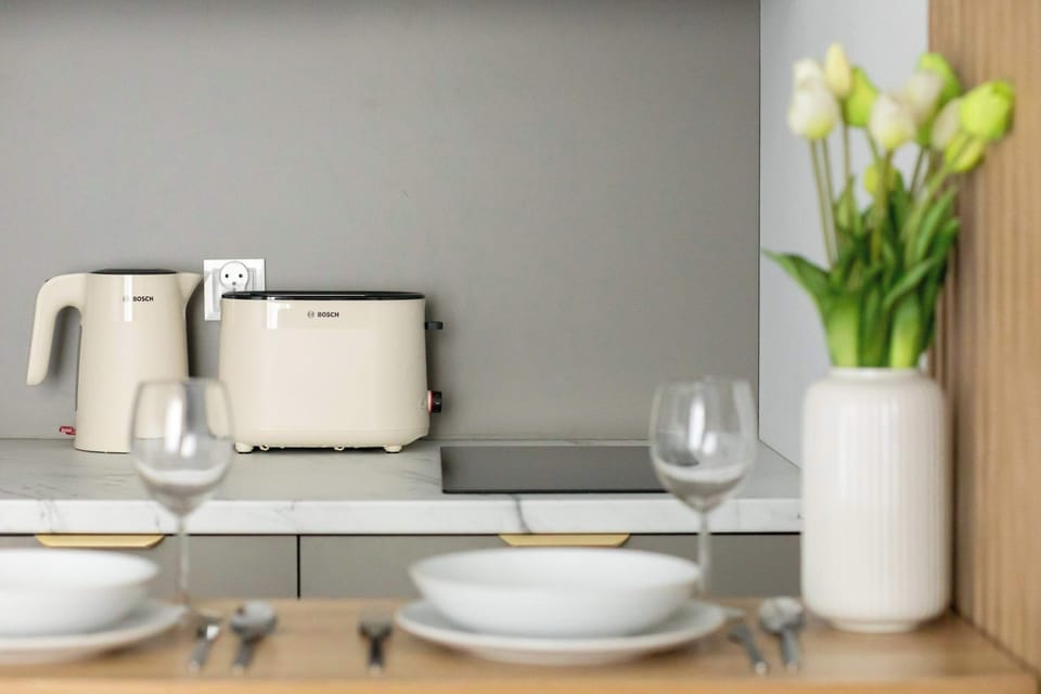A neatly arranged dining table with tableware and fresh flowers. It's a lovely spot to enjoy your morning coffee or a home cooked meal.