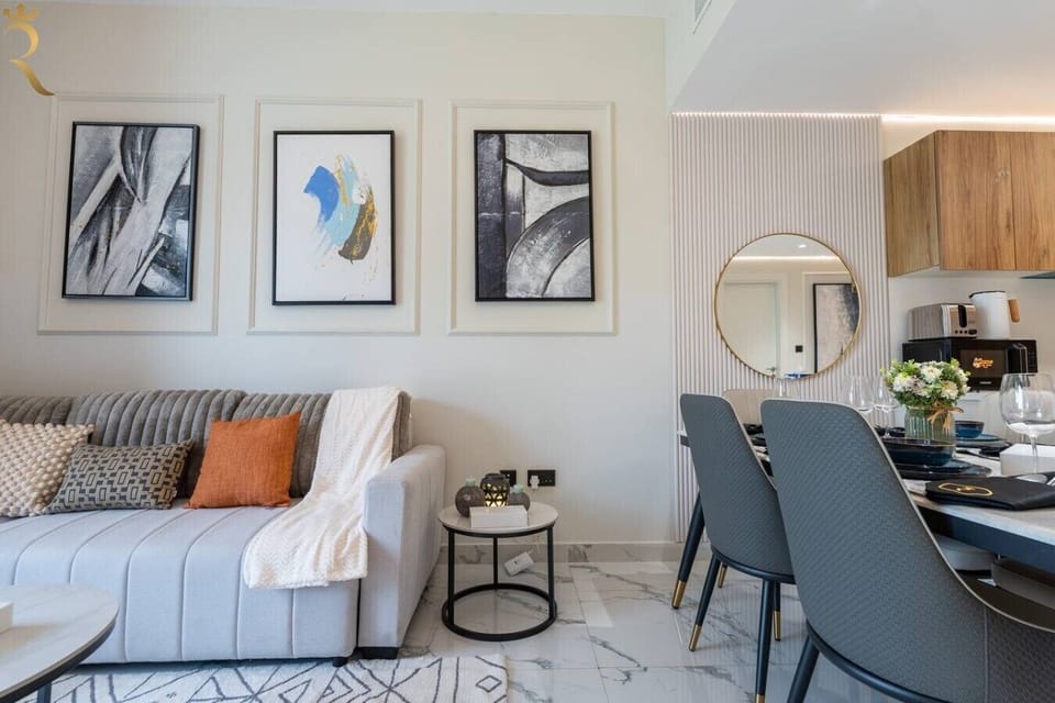 Open-plan living and dining space with a cozy sofa, elegant art pieces, and a sleek dining set framed by a statement round mirror.