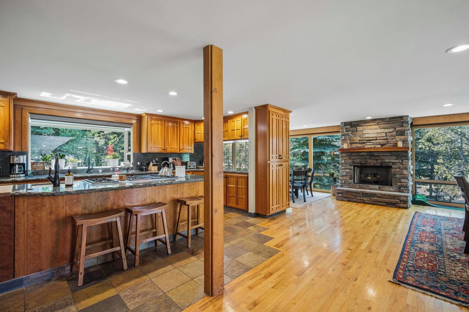 Gather around your spacious kitchen island with gorgeous granite countertops and gleaming wood cabinetry. Large windows frame lush trees, and a cozy stone fireplace sets the scene for relaxed evenings together.
