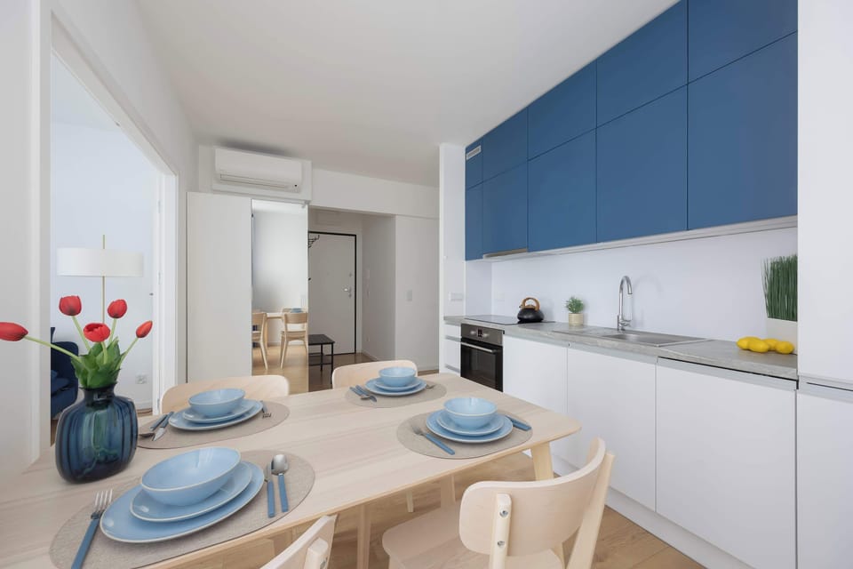 A modern dining area with a table set for a meal, positioned beside the fully equipped kitchen. The open design encourages comfortable shared dining.