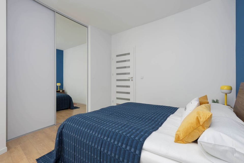A front-facing view of the bedroom with a neatly made bed framed by matching bedside tables and decorative artwork. The balanced design creates a relaxing atmosphere.