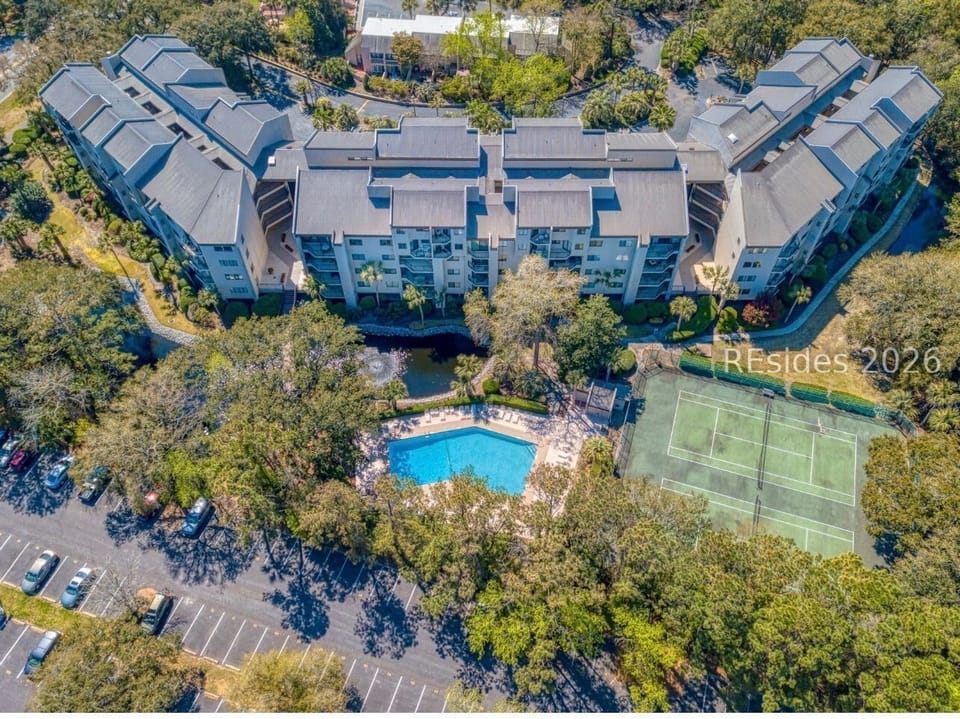 Azure water sparkles in the center of this verdant estate, offering a refreshing escape among the oaks. A private tennis court and manicured paths invite slow afternoons of sport and leisure in the bright, open air.