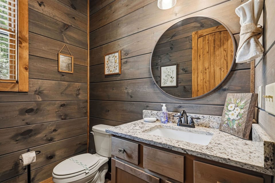 Step into your rustic-chic bathroom with warm wood paneling, a sleek granite vanity, and charming botanical accents that create a cozy, nature-inspired retreat.