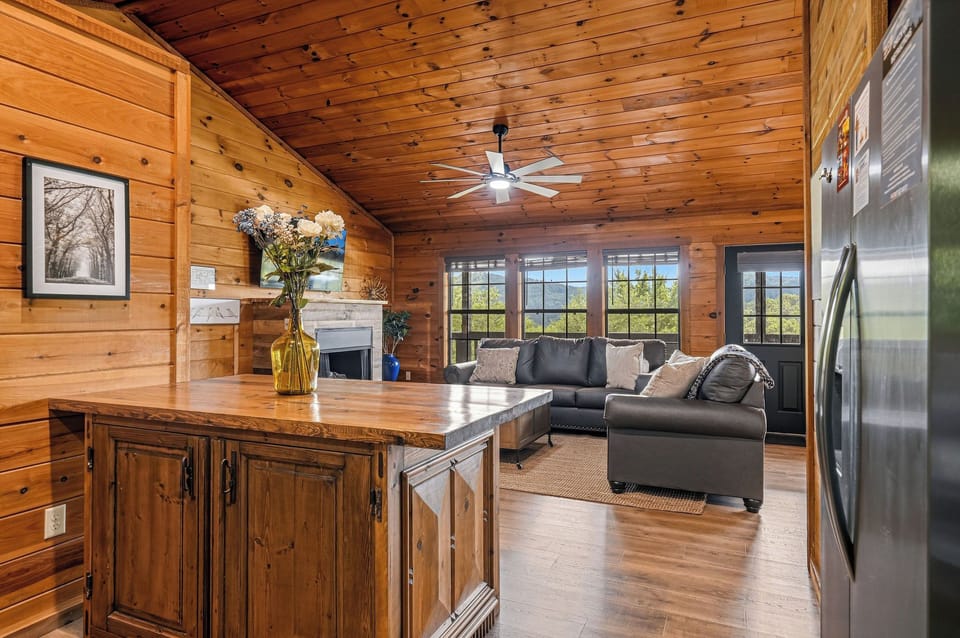 Sunlight pours through tall windows into your open living space, where warm wood wraps you in cabin charm and a cozy sectional invites relaxation after mountain adventures.