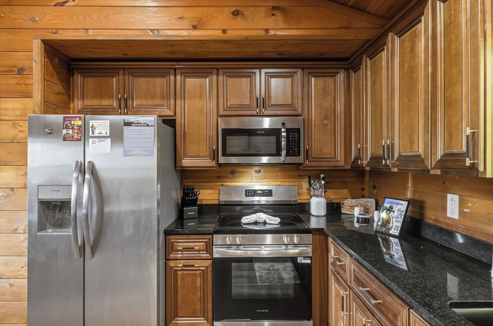 Full kitchen with rich wood cabinets, modern appliances, and sleek granite counters, ready for cooking memorable meals during your stay.