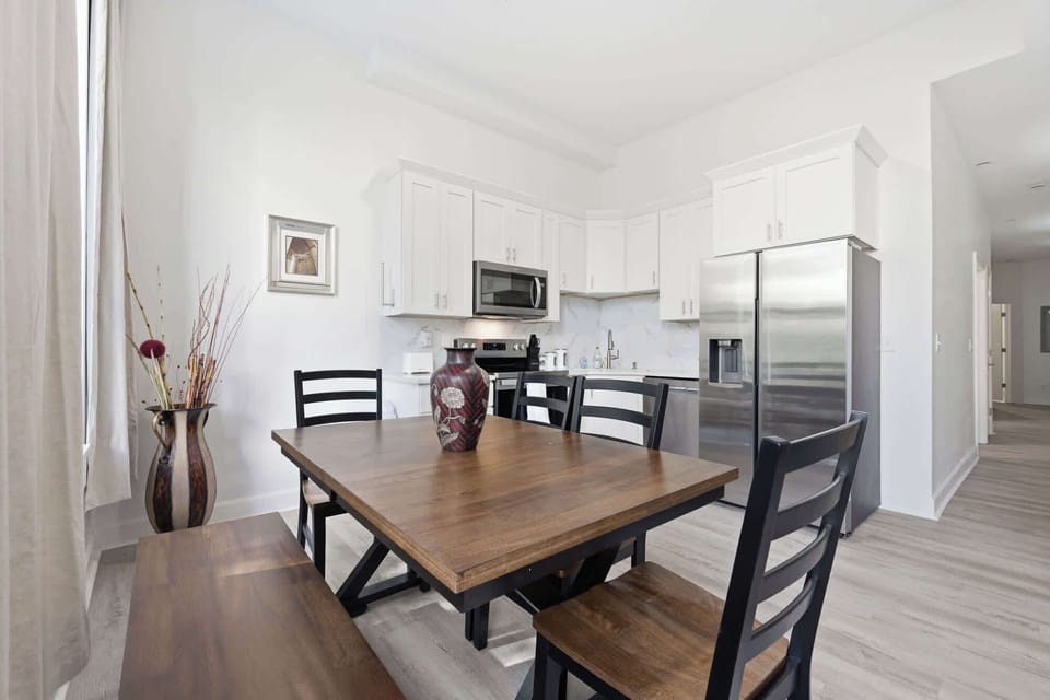 Kitchen | Full view of the kitchen with white cabinetry, stainless steel appliances, and a wood dining table right alongside.
