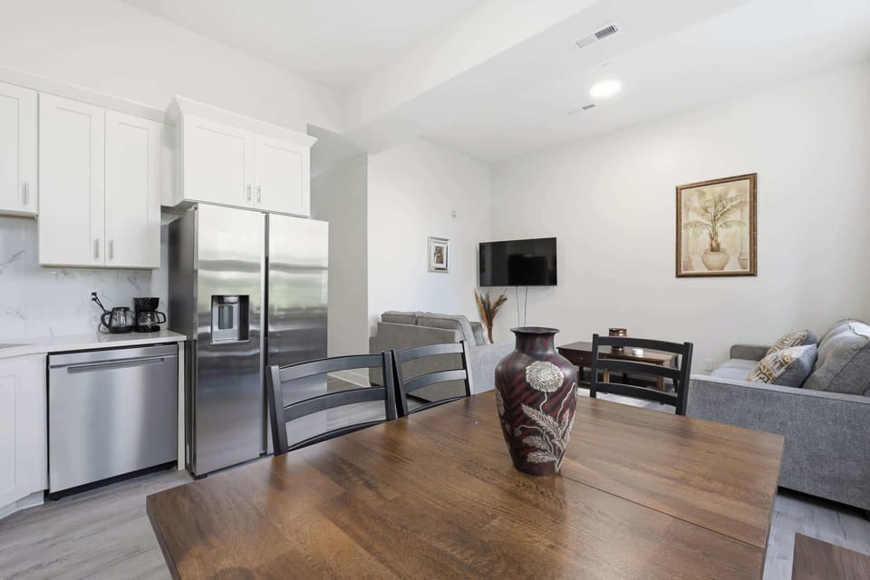 Dining Room | Open-concept space with a wood dining table, stainless steel kitchen appliances, and a cozy living area just beyond.
