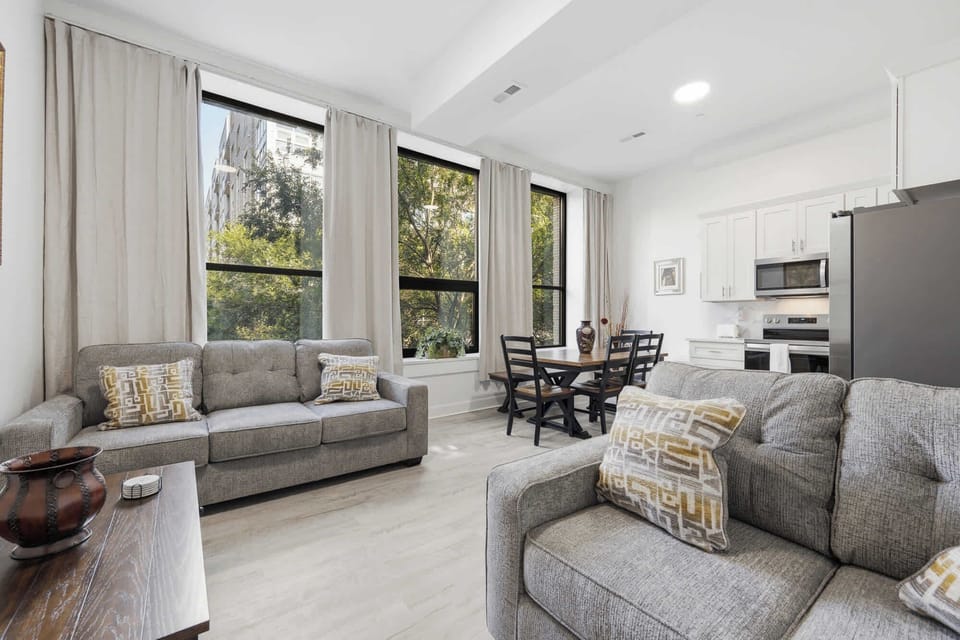Living Room | Comfortable seating for the whole group, with tall windows framing city and treetop views over 4th Street.