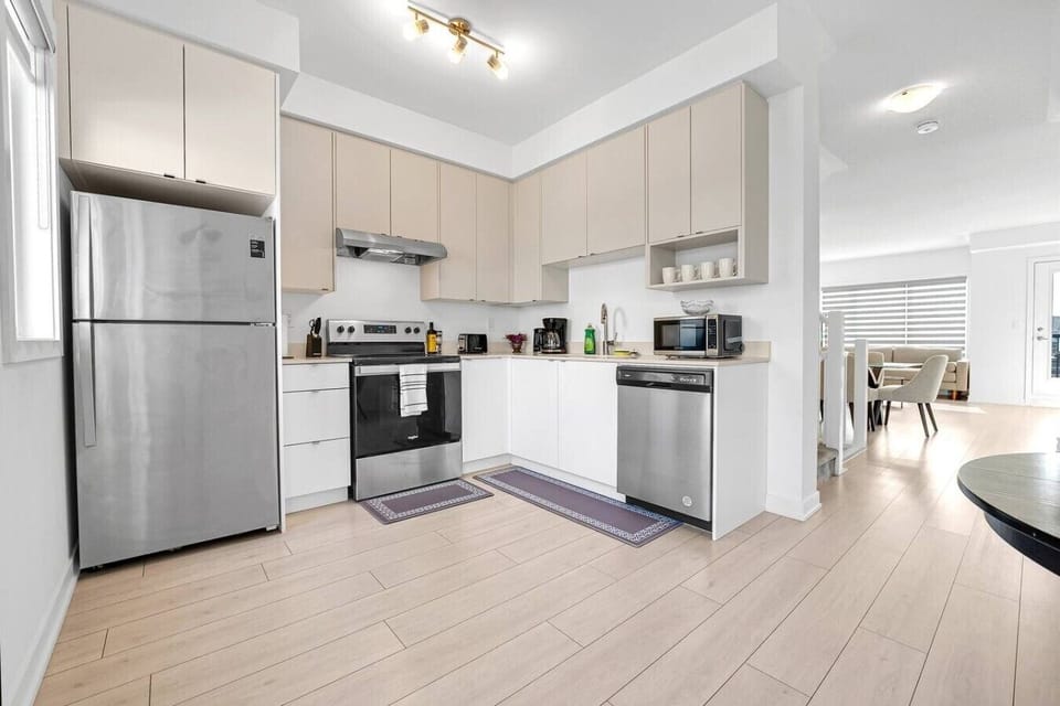 A modern, fully equipped kitchen featuring stainless steel appliances, light wood cabinetry, and white counters—perfect for cooking a family feast or preparing snacks before an outing.