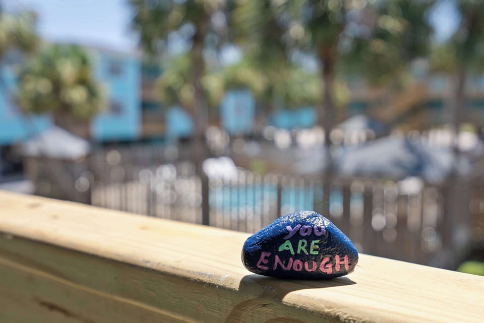 A cheerful coastal detail overlooking the pool area reminds guests that they are always enough.