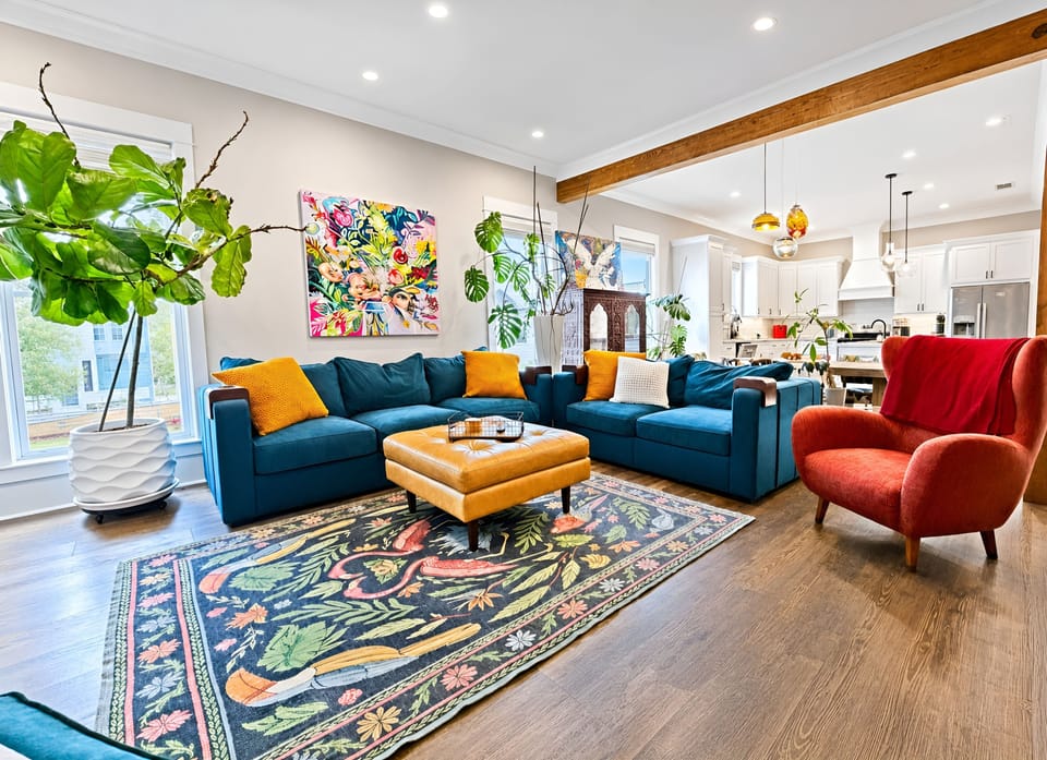 Airy living room with exposed beams, wood floors, and high ceilings.