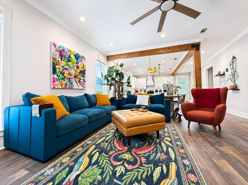 Airy living room with exposed beams, wood floors, and high ceilings.