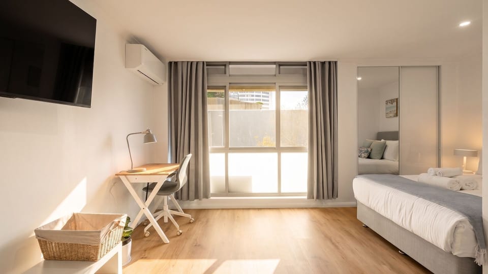 Peaceful bedroom with Smart TV and workstation.
