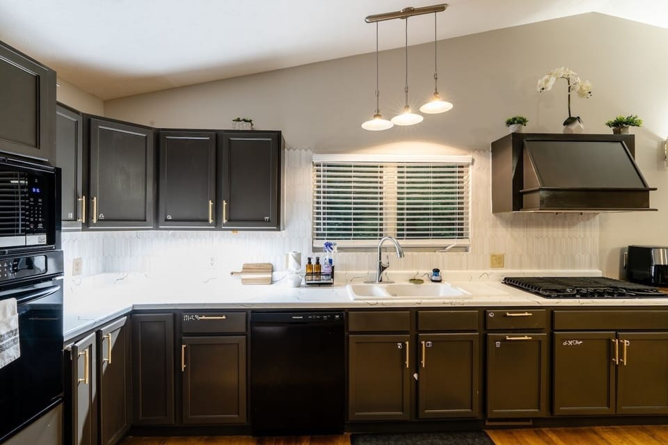 Modern kitchen with dark cabinets, gas cooktop, and bright window