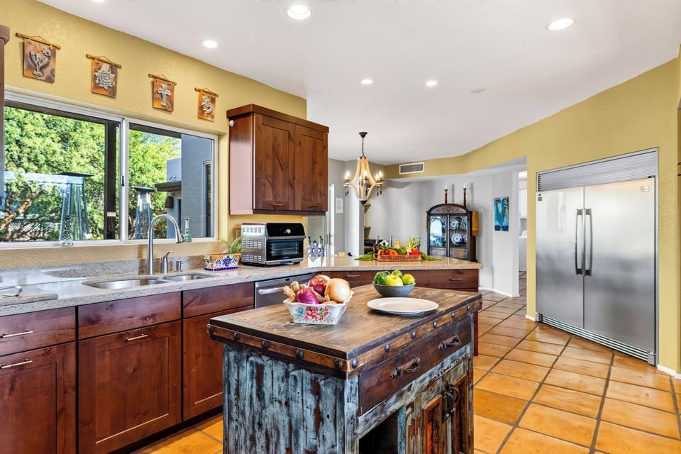A rustic prep island anchors the kitchen, with stainless steel appliances and red-rock glimpses beyond the adjoining dining area.
